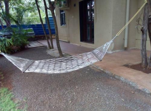 a hammock in a yard in front of a building at Classic Villa 3 BHK Villa with pool in chondhi, Kihim, Alibag in Alibag