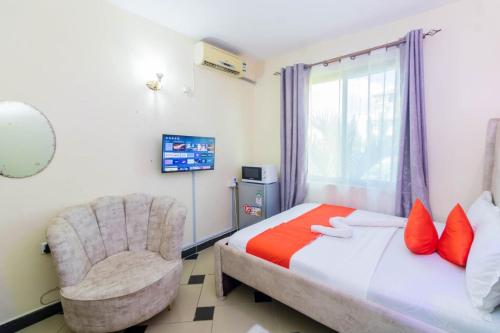 a bedroom with a bed and a chair and a window at Greer Homes Sun Sweet in Shanzu