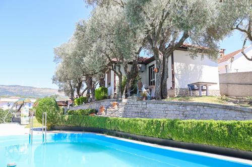 a swimming pool in front of a house with trees at Hilja's Oliven Garden Bungalows in Ulcinj
