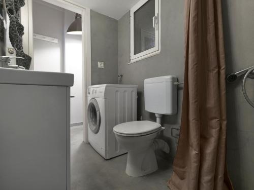 uma casa de banho com um WC e uma máquina de lavar roupa em The Acropolis Apartment em Atenas