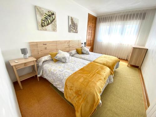 Un dormitorio con una cama grande con una manta amarilla. en Apartamento Rivela, en Burela de Cabo