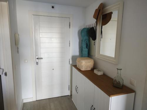 a kitchen with white cabinets and a mirror and a door at Apartamento playa y golf I Retamar in Retamar