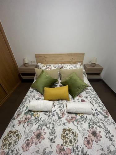 1 cama con colcha floral y almohadas en O LAR DE MARTINA, en Redondela