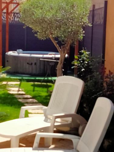 2 chaises blanches et un arbre dans la cour dans l'établissement Maison 4 à 6 pers Quartier calme Tout confort, à Aigues-Mortes