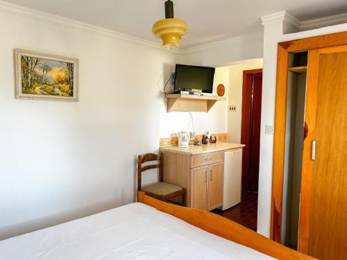 a bedroom with a bed and a desk with a television at Hilja's Oliven Garden Bungalows in Ulcinj