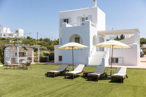 a group of chairs and umbrellas in front of a house at Naxian Resort in Aliko Beach