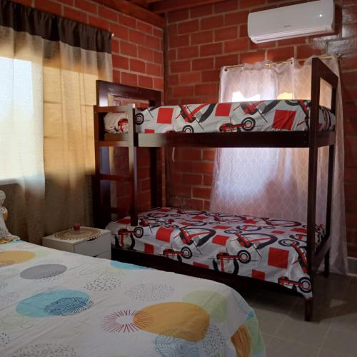 2 Etagenbetten in einem Zimmer mit Ziegelwand in der Unterkunft PLAYA DEL REY in Carrizal