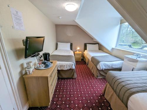 a hotel room with two beds and a tv at The George Guest House in Plymouth