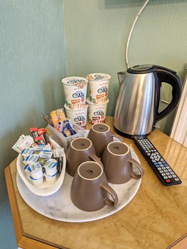 a table with a plate with cups and a tea kettle at The George Guest House in Plymouth
