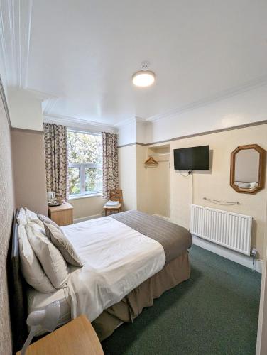 a bedroom with a bed and a flat screen tv at The George Guest House in Plymouth