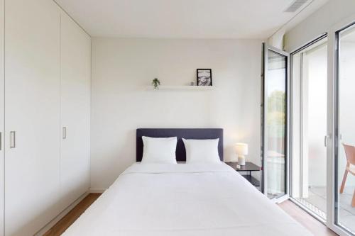 a white bedroom with a large bed and a window at Lodges Hotel Morges in Morges