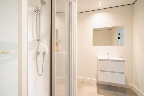 Un baño blanco con ducha y lavabo. en Opera Square Apartments in Antwerp Centre, en Amberes