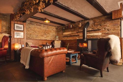 a living room with a leather couch and a fireplace at Port William Inn in Tintagel