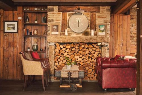 a living room with a fireplace with a clock on the wall at Port William Inn in Tintagel