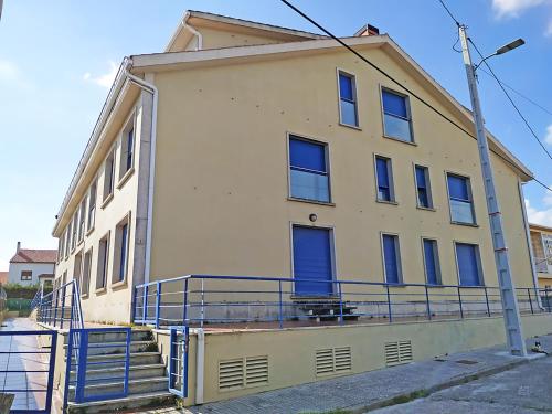 un edificio giallo con finestre blu e luce di strada di Apartamentos Aguiño Ribeira 3000 a Ribeira