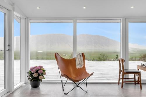 a chair and a vase of flowers in front of a window at Himri the mountain villa in Mosfellsbær
