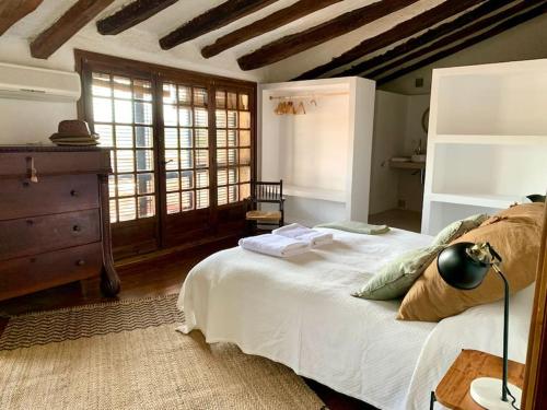 1 dormitorio con cama blanca y techo de madera en Els Racons del Fort Castle hosting up to 18 people, en Capmany