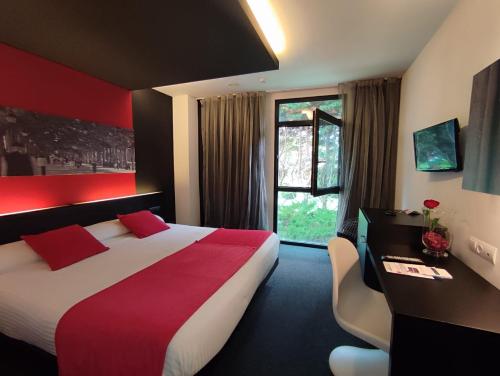 a hotel room with a bed and a desk and a window at Hotel Playa Ribera in Suances