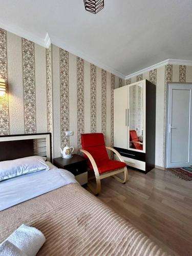 a bedroom with a bed and a red chair at Hotel Marioni in Tbilisi City