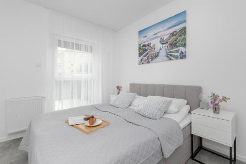 a white bedroom with a bed with a tray on it at Modern Apartment Close to the Beach in Gdańsk by Noclegi Renters in Gdańsk