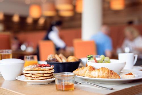 a table with plates of breakfast food on it at Upstalsboom Kühlungsborn in Kühlungsborn
