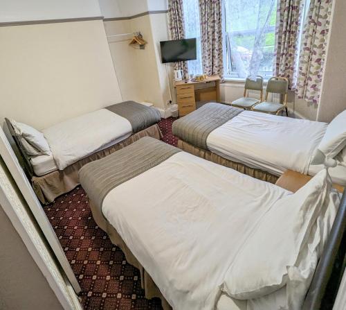 a hotel room with three beds and a television at The George Guest House in Plymouth