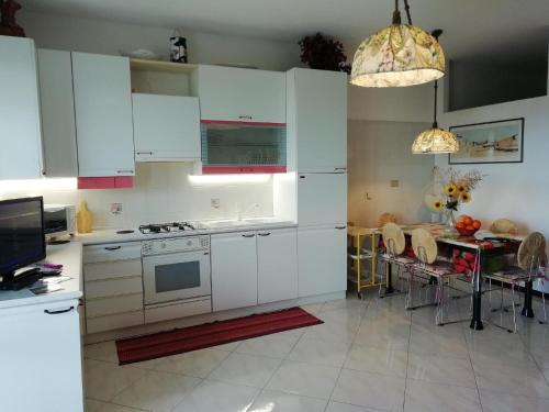 cocina con armarios blancos y mesa de comedor en Ferienwohnung mit Balkon mit Meerblick und Autostellplatz, en Mascali