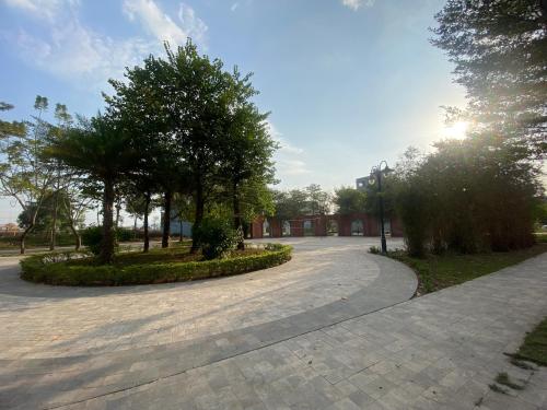einen Gehweg in einem Park mit Bäumen und einem Gebäude in der Unterkunft Khách Sạn Thắng Lợi 2 Bắc Giang in Làng Thành