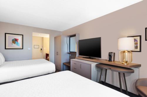a hotel room with two beds and a desk with a television at Holiday Inn St Johns by IHG in St. John's