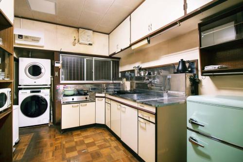 a large kitchen with white cabinets and a washer and dryer at Roopt仙台薬師堂 in Sendai