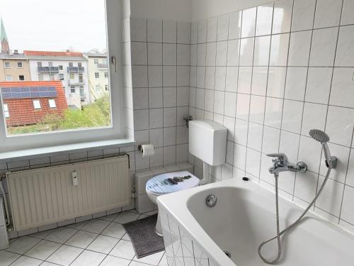 een badkamer met een bad, een toilet en een raam bij Citywohnung mit Gartenzugang in Schwerin
