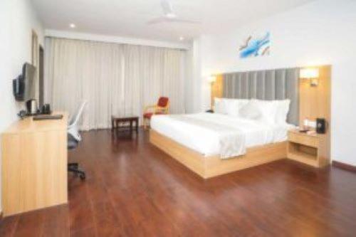 Comfort Inn, Udaipur في أودايبور: غرفة نوم بسرير ابيض وارضية خشبية