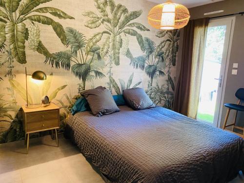 a bedroom with a bed with a tropical wallpaper at Le Saint Marin in Chatuzange-le-Goubet