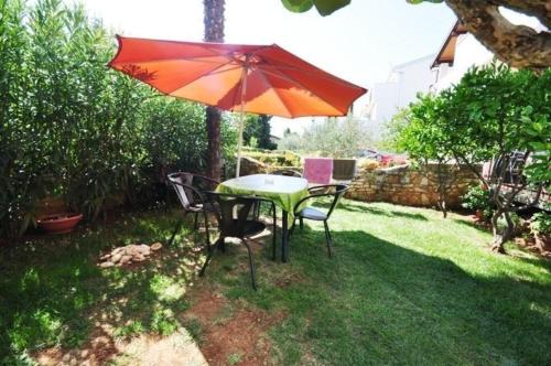 a table and chairs under an umbrella in a yard at Ferienwohnung in Novigrad mit privatem Parkplatz in Karpinjan