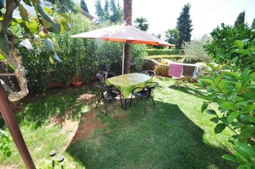 a table and chairs with an umbrella in a yard at Ferienwohnung in Novigrad mit privatem Parkplatz in Karpinjan