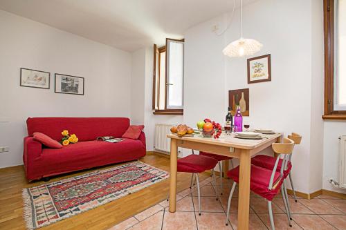 ein Wohnzimmer mit einem roten Sofa und einem Tisch in der Unterkunft Appartamento Centro Storico Riva 2 - Happy Rentals in Riva del Garda