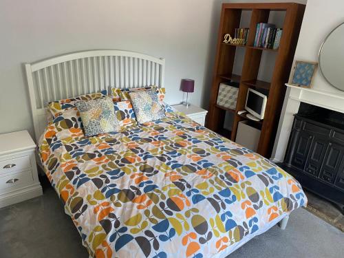 a bed with a colorful comforter in a bedroom at The Annexe @ Woodland in Bury