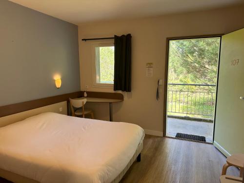 een slaapkamer met een bed en een groot raam bij Hôtel Ecochic, Mont-de-Marsan Sud in Saint-Pierre-du-Mont
