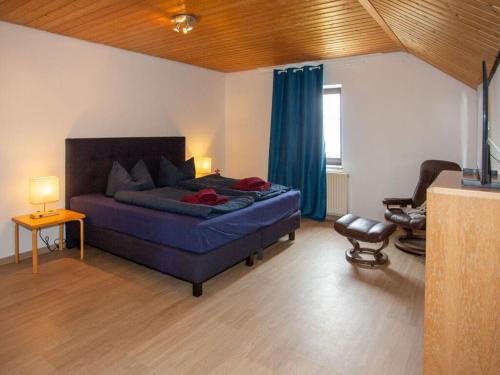 a bedroom with a blue bed and a chair at am Wehr Comfortable holiday residence in Allersberg