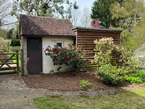 a small cabin with a door and some flowers at The Annexe @ Woodland in Bury