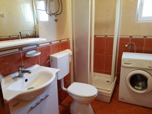 een badkamer met een wastafel en een wasmachine bij The POINTE Apartment in Novalja