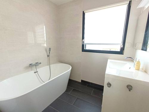 une salle de bain avec une baignoire et un lavabo dans l'établissement Maison neuve 4* avec Sauna, WIFI à 150m de la plage - Pleumeur-Bodou - FR-1-368-139, à Pleumeur-Bodou