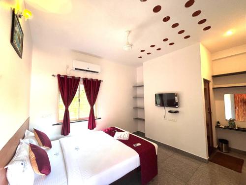 a bedroom with a large white bed with red curtains at De Capital Hotel with Swimming Pool in Puducherry