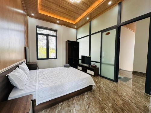 a bedroom with a large bed and a television at HeniSi Hotel Măng Đen (HeniSi 2) in Kon Von Kla