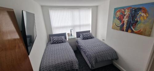 a room with two beds in front of a window at LFC Anfield Guest House in Liverpool