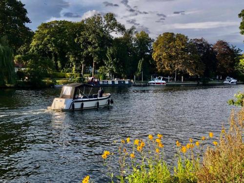 Ein Boot auf einem Fluss mit Leuten darauf. in der Unterkunft Cozy double bedroom in stunning Bungalow on River Thames - near Thorpe Park/Royal Holloway University/20mins from Heathrow in Staines upon Thames
