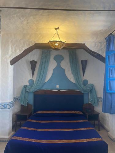 a bedroom with a blue bed and a chandelier at Riad Al Madina in Essaouira