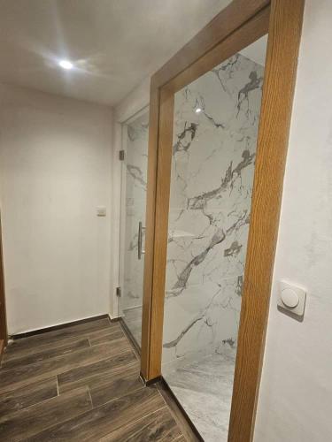 a bathroom with a marble wall and a glass door at Bark Luxury Appartments @Signal Abidjan Plateau in Abidjan