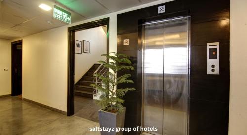 an elevator in a building with a potted plant next to it at Saltstayz Thyme - New Friends Colony in New Delhi