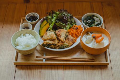 a wooden tray with a plate of food and chopsticks at Ten to Sen Guesthouse in Takamatsu